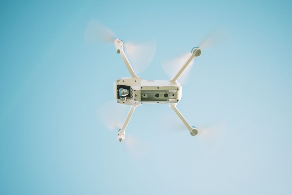 Een witte drone in de lucht onder een blauwe hemel