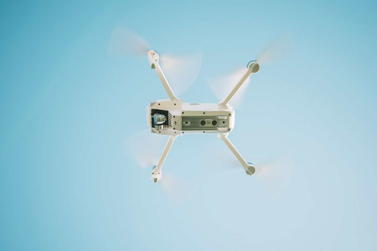 Een witte drone in de lucht onder een blauwe hemel